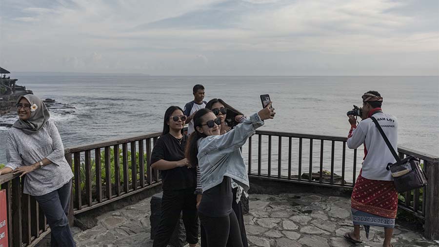 Pengunjung berswafoto di Tanah Lot, Bali, Rabu (14/12/2022). (Nyimas Laula/Bloomberg)