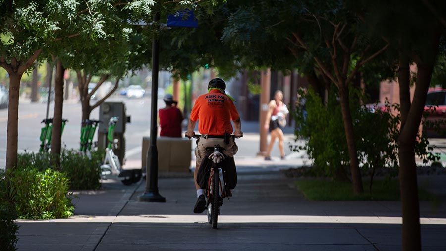 Warga mengendarai sepeda sambil mengenakan handuk pendingin saat gelombang panas di Phoenix, Arizona, AS, Kamis (20/7/2023) (Caitlin O'Hara/Bloomberg)