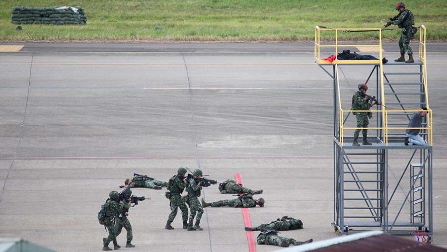 Para tentara yang berperan sebagai perusuh terlibat baku tembak dengan polisi bandara. (I-Hwa Cheng/Bloomberg)