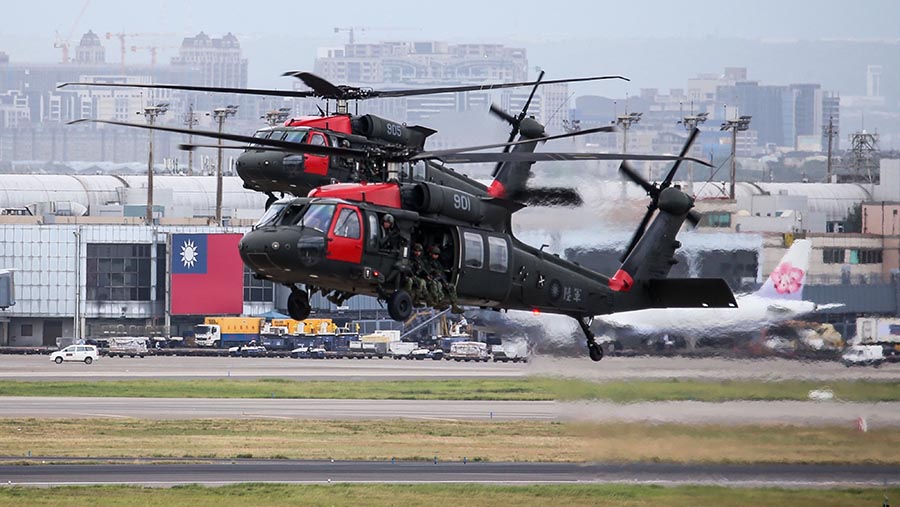 Terlihat tentara membawa senapan yang berlari di landasan pacu untuk melawan pasukan musuh yang diangkut oleh helikopter. (I-Hwa Cheng/Bloomberg)