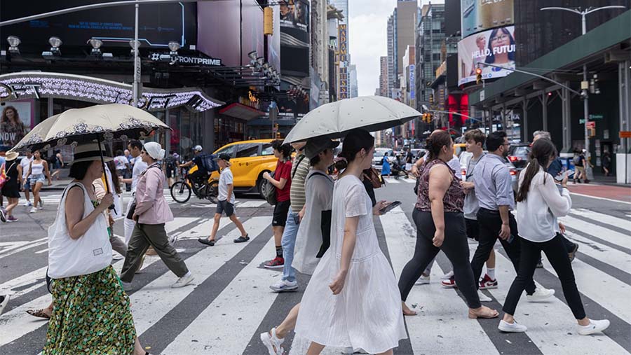 Pejalan kaki memegang payung untuk perlindungan dari matahari selama gelombang panas di New York, AS, Kamis (27/7/2023). (Jeenah Moon/Bloomberg)