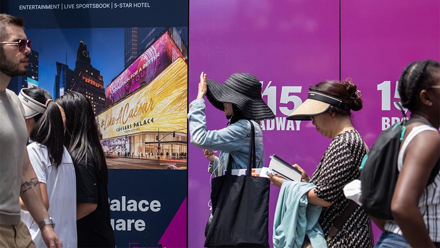 Pejalan kaki mengenakan topi selama gelombang panas di New York, AS, Kamis (27/7/2023). (Jeenah Moon/Bloomberg)