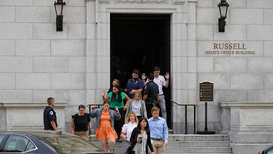 Anggota staf keluar dari Gedung Kantor Senat Russell dengan tangan terangkat di Capitol Hill, Washington DC, AS, Rabu (2/8/2023). (Al Drago/Bloomberg)