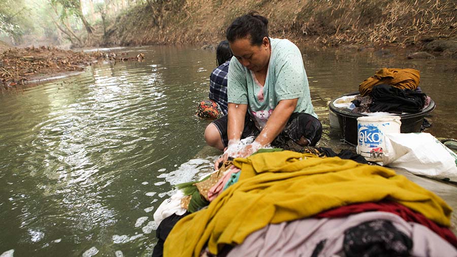 Warga mencuci pakaian saat musim kemarau di kali Cihoe, Cibarusah, Kab. Bekasi, Jawa Barat, Jumat (4/8/2023). (Bloomberg Technoz/ Andrean Kristianto)