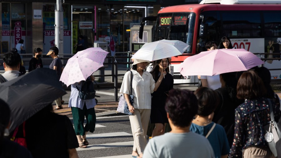 Pejalan kaki berlindung dari terik matahari di bawah payung di Seoul, Korea Selatan. (SeongJoon Cho/Bloomberg)