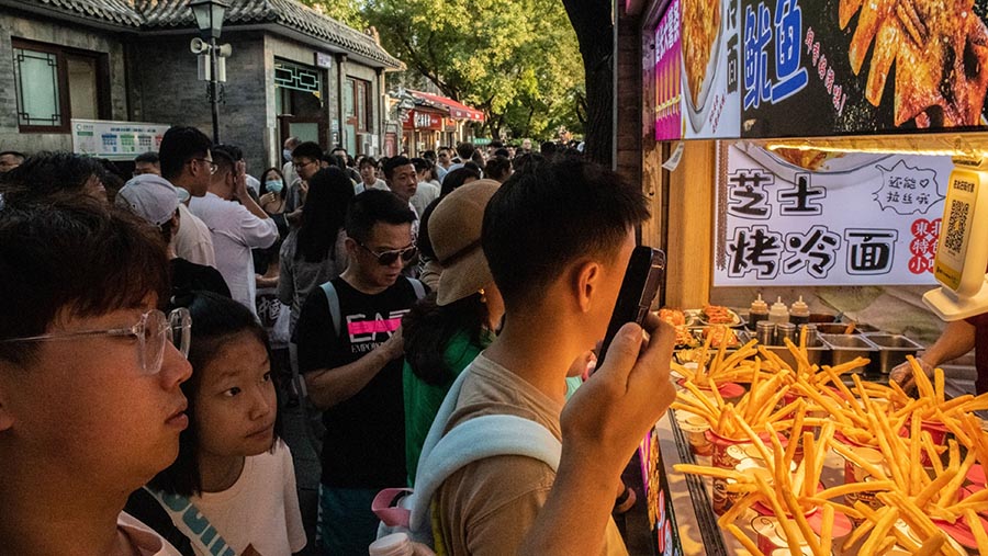 Pengunjung berbelanja di Nanluoguxiang di Beijing, China, Sabtu (12/8/2023). (Bloomberg)


