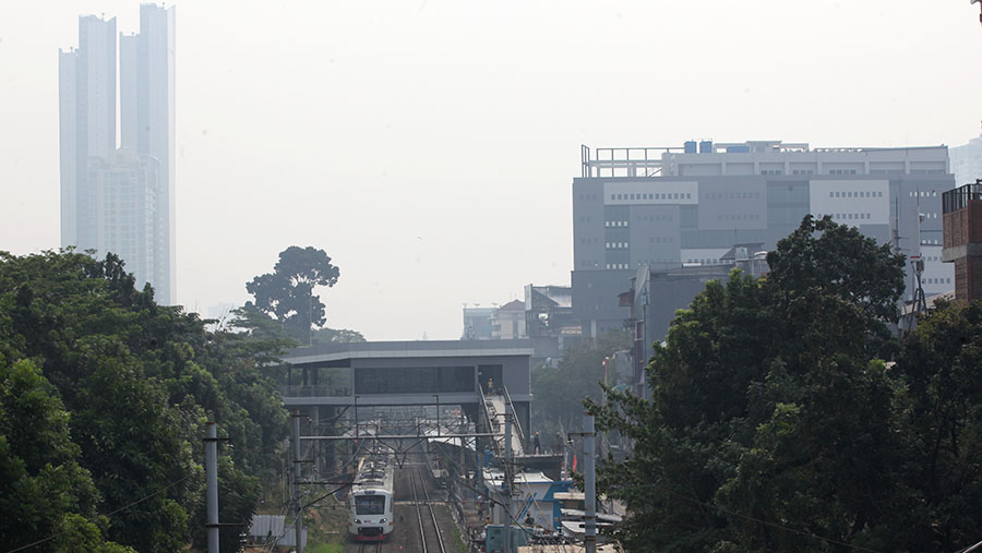 Kereta melintas dengan latar gedung diselimuti polusi di Jakarta, Rabu (23/8/2023). (Bloomberg Technoz/ Andrean Kristianto)