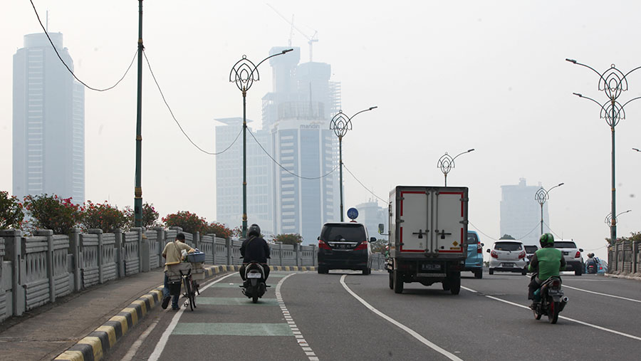 Suasana lalu lintas dengan latar gedung diselimuti polusi di Jakarta, Rabu (23/8/2023). (Bloomberg Technoz/ Andrean Kristianto)