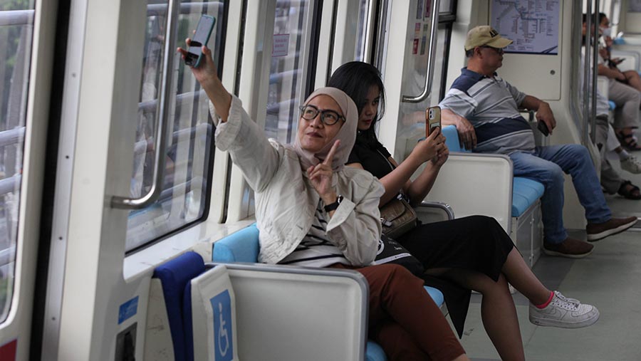 Warga berfoto didalam gerbong kereta LRT Jabodebek dihari pertama beroperasi di Jakarta, Senin (28/8/2023). (Bloomberg Technoz/ Andrean Kristianto)