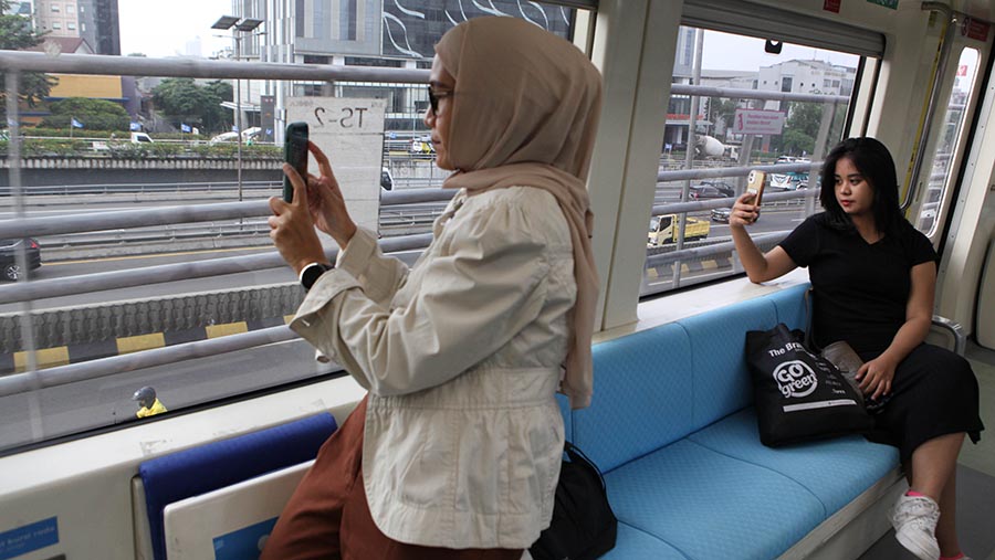 Warga berfoto didalam gerbong kereta LRT Jabodebek dihari pertama beroperasi di Jakarta, Senin (28/8/2023). (Bloomberg Technoz/ Andrean Kristianto)