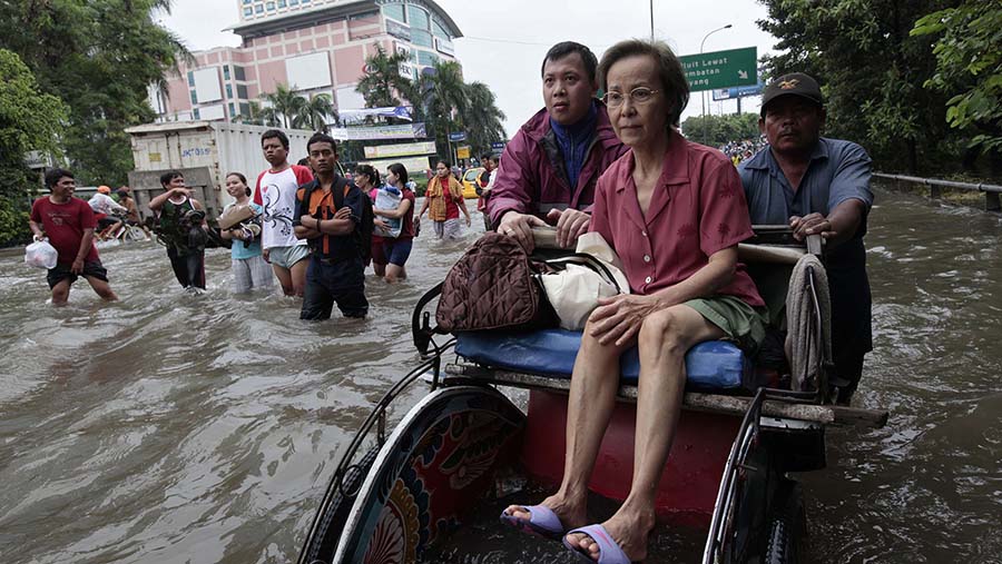 Seorang wanita diangkut melalui banjir dengan becak di Jakarta, Jumat (18/1/2013). (Dimas Ardian/Bloomberg)