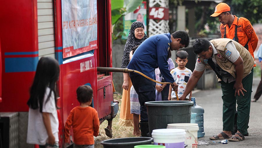 Mereka menjejerkan ember dan galon airnya untuk mengantre mengisi air. (Bloomberg Technoz/Andrean Kristianto)