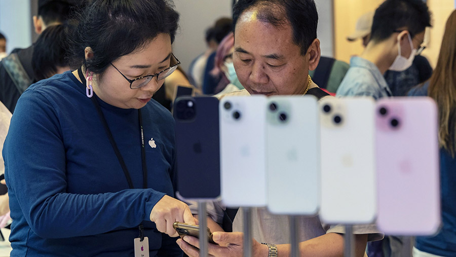Karyawan melayani pelanggan saat hari pertama penjualan smartphone apple iPhone 15 di toko Apple Inc. di Shanghai, China, Jumat (22/9/2023). (Bloomber