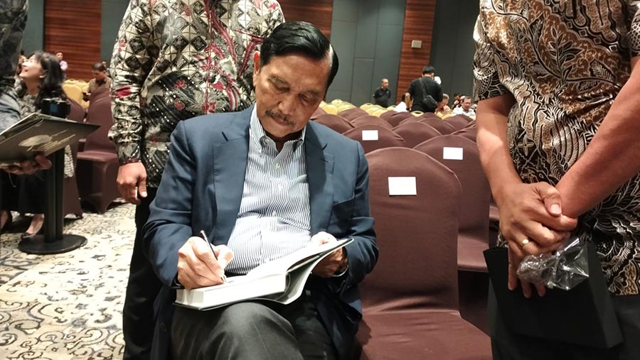 Menko Marves, Luhut Binsar Panjaitan menandatangani buku saat perayaan ulang tahunnya. (Bloomberg Technoz/ Sultan Ibnu Affan)