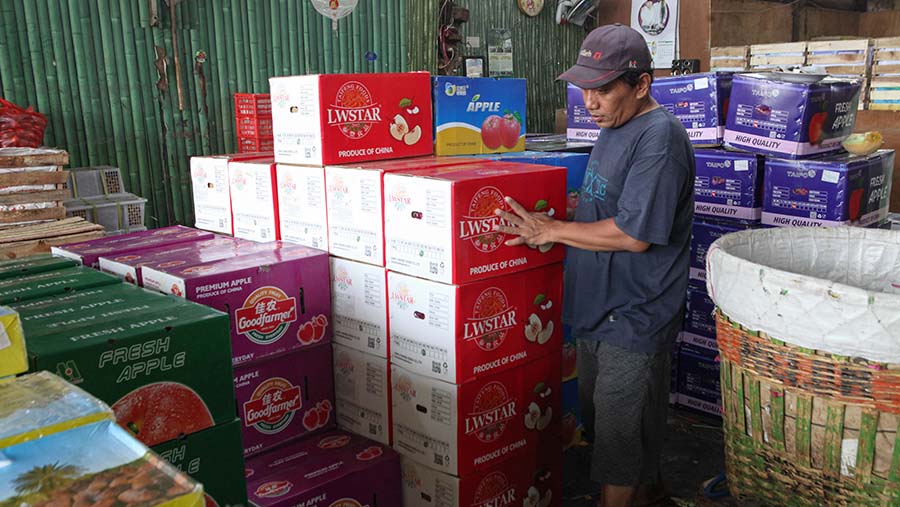 Pedagang memindahkan dus buah impor asal China yang dijual di Pasar Induk Kramat Jati, Jumat (6/10/2023). (Bloomberg Technoz/Andrean Kristianto)