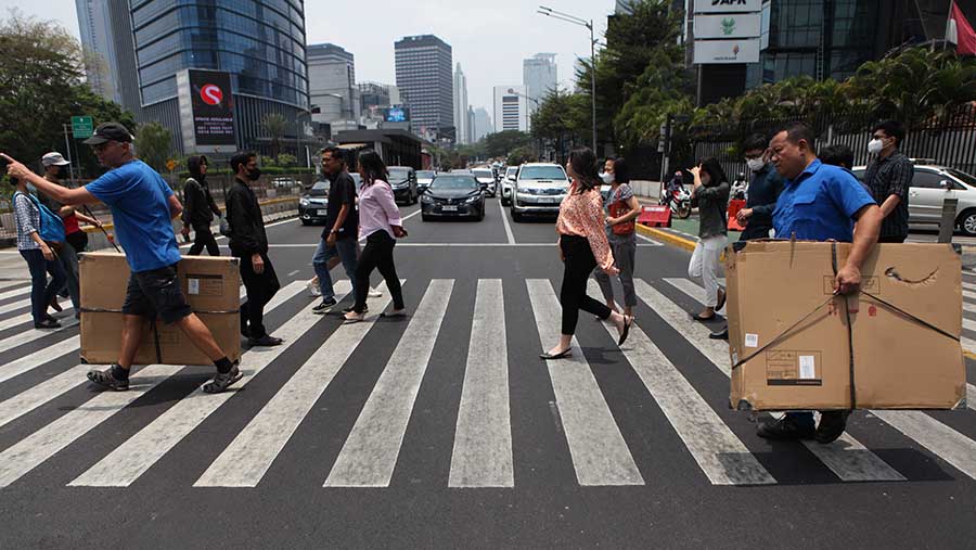 Pejalan kaki menyeberang saat hari tanpa bayangan di Jakarta, Senin (9/10/2023). (Bloomberg Technoz/Andrean Kristianto)