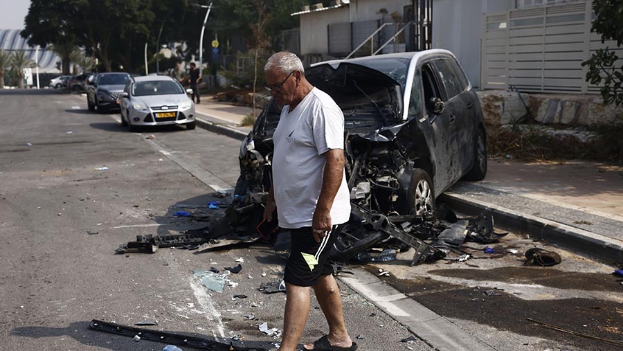 Seorang warga melewati mobil yang terbakar usai serangan militan Palestina Hamas di Sderot, Israel, pada Minggu (8/10/2023). (Kobi Wolf/Bloomberg)