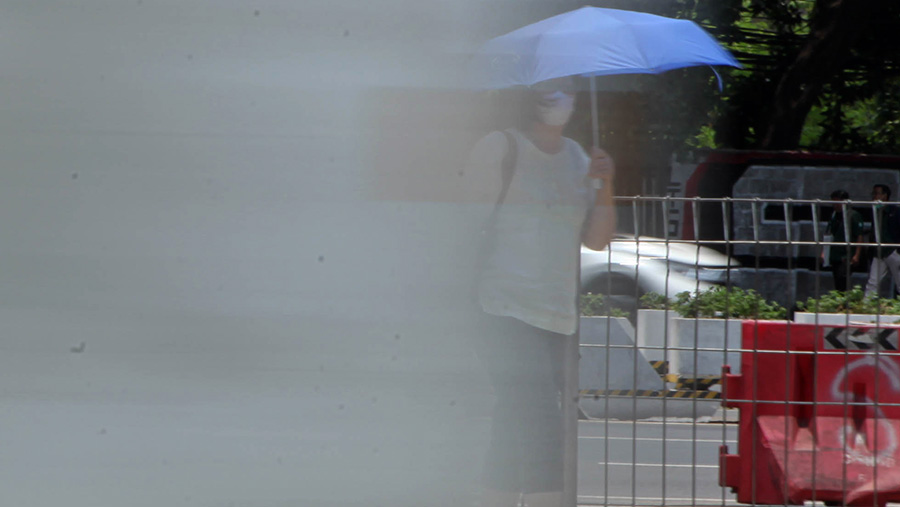 Warga menggunakan payung saat cuaca panas di Jakarta, Selasa (10/10/2023). (Bloomberg Technoz/Andrean Kristianto)