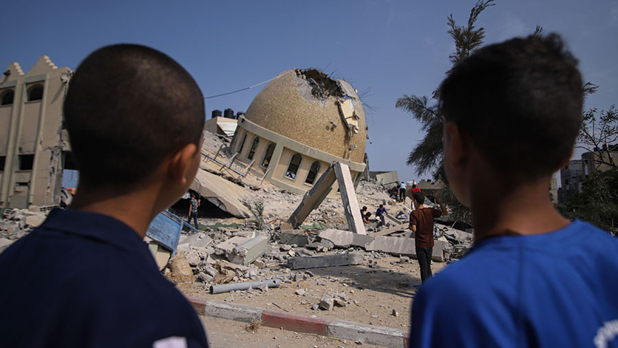 Orang-orang melihat masjid yang hancur usai serangan udara Israel di Khan Younis, Jalur Gaza, Minggu (8/10/2023). (Ahmad Salem/Bloomberg)