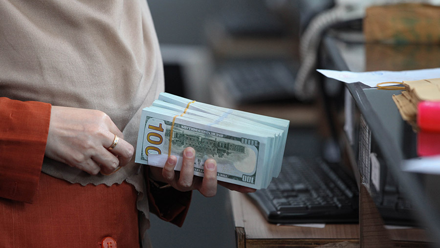 Pelanggan memegang uang dolar AS di salah satu pusat penukaran uang di Jakarta, Rabu (11/10/2023). (Bloomberg Technoz/Andrean Kristianto)