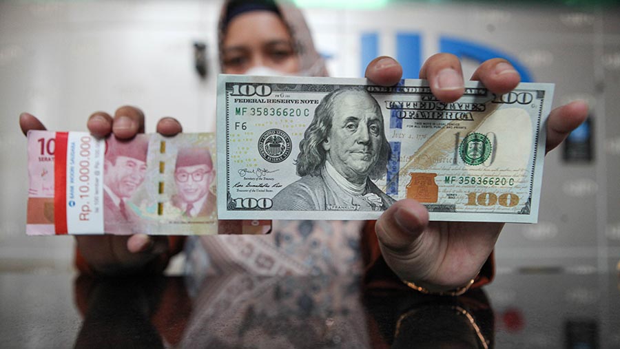 Karyawan memperlihatkan uang dolar AS dan rupiah di pusat penukaran uang di Jakarta, Rabu (11/10/2023). (Bloomberg Technoz/Andrean Kristianto)