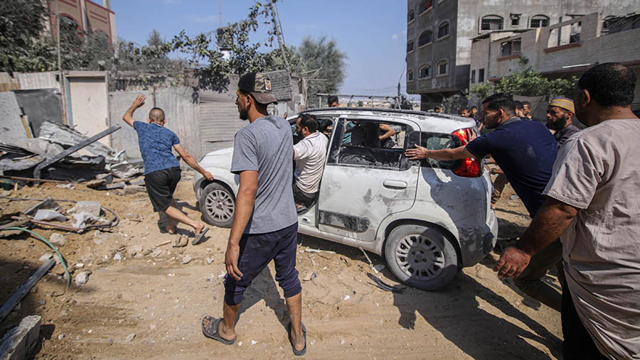 Warga Palestina memindahkan mobil yang rusak pasca serangan udara Israel di lingkungan Al-Amal, Jalur Gaza, Rabu (11/10/2023). (Ahmad Salem/Bloomberg)