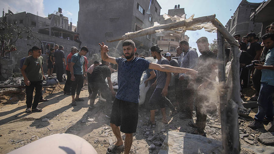 Warga Palestina membersihkan puing-puing pasca serangan udara Israel di lingkungan Al-Amal, Jalur Gaza, Rabu (11/10/2023). (Ahmad Salem/Bloomberg)