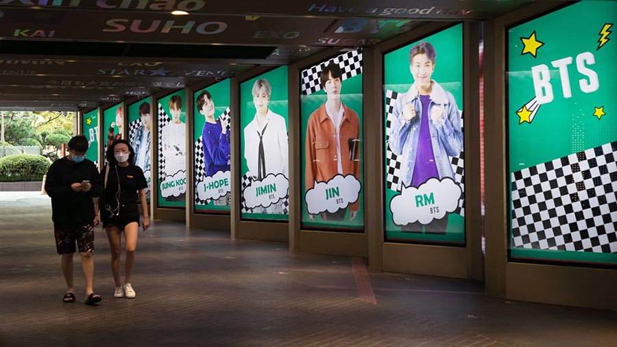 Pejalan kaki melewati iklan boy band K-pop BTS di Seoul, Korea Selatan, Jumat (18/9/2023). (SeongJoon Cho/Bloomberg)