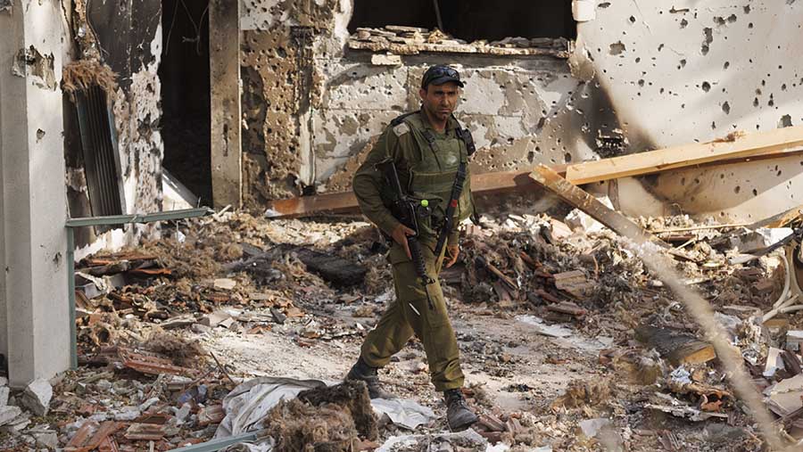 Seorang tentara Israel berjalan di antara puing-puing rumah yang hancur di Kibbutz Be'eri, Israel, Minggu (22/10/2023). (Kobi Wolf/Bloomberg)