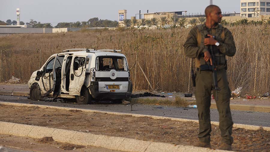 Tentara Israel di samping kendaraan yang terkena roket yang ditembakkan militan Hamas di Netivot, Israel, Minggu (22/10/2023). (Kobi Wolf/Bloomberg)