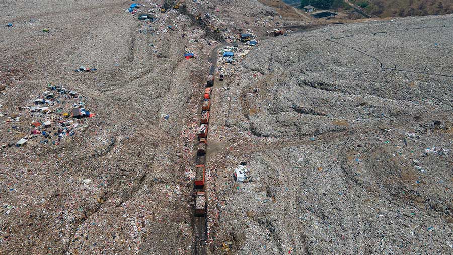 Mobil truk sampah terlihat mengantre untuk menurunkan sampah. (Bloomberg Technoz/Andrean Kristianto)