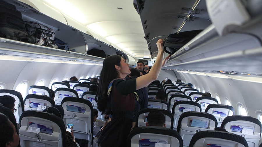 Pramugari memasukan koper penumpang kedalam bagasi kabin di Bandara Soekarno-Hatta, Tangerang, Rabu (1/11/2023) (Bloomberg Technoz/Andrean Kristianto)