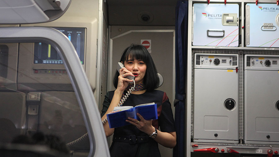 Pramugari memberikan pengumuman kepada penumpang di Bandara Soekarno-Hatta, Tangerang, Rabu (1/11/2023). (Bloomberg Technoz/Andrean Kristianto)