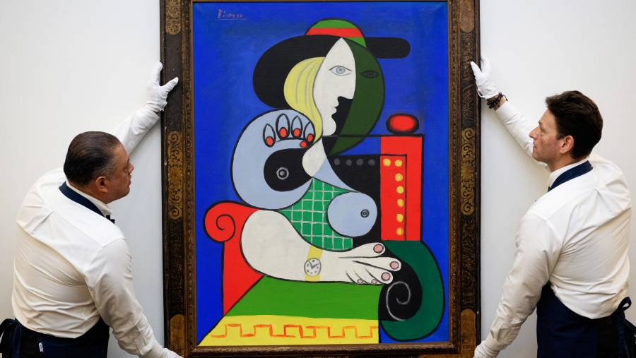 Sotheby’s art handlers adjust Pablo Picasso’s Femme à la montre, from the Emily Fisher Landau Collection. (Sumber: Bloomberg)