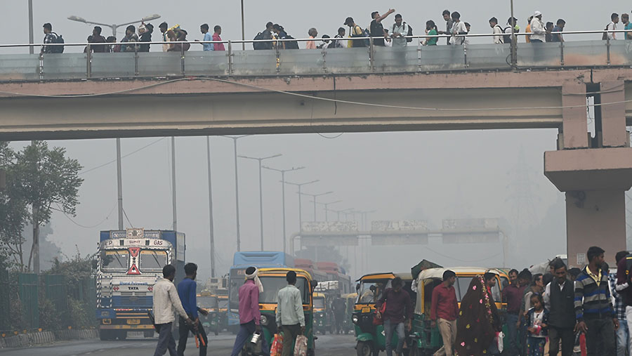 Penumpang menyeberang jalan saat kabut polusi tebal di New Delhi, India, Sabtu (4/11/2023). (Prakash Singh/Bloomberg)