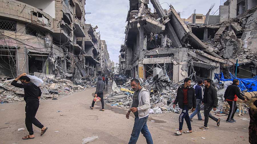 Warga Palestina lewat bangunan hancur pada hari kedua gencatan senjata di kamp pengungsi Nuseirat, Gaza, Sabtu (25/11/2023). (Ahmad Salem/Bloomberg)