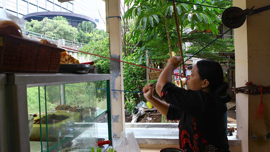 Pedagang mengerek makanan pesanan di Warung Kerek Ember di Kuningan Barat, Jakarta, Selasa (5/12/2023) (Bloomberg Technoz/Andrean Kristianto)