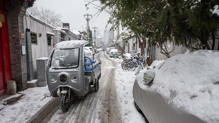 Sebuah kendaraan melaju di sepanjang jalan yang tertutup salju di Beijing, China, Kamis (14/12/2023). (Bloomberg)