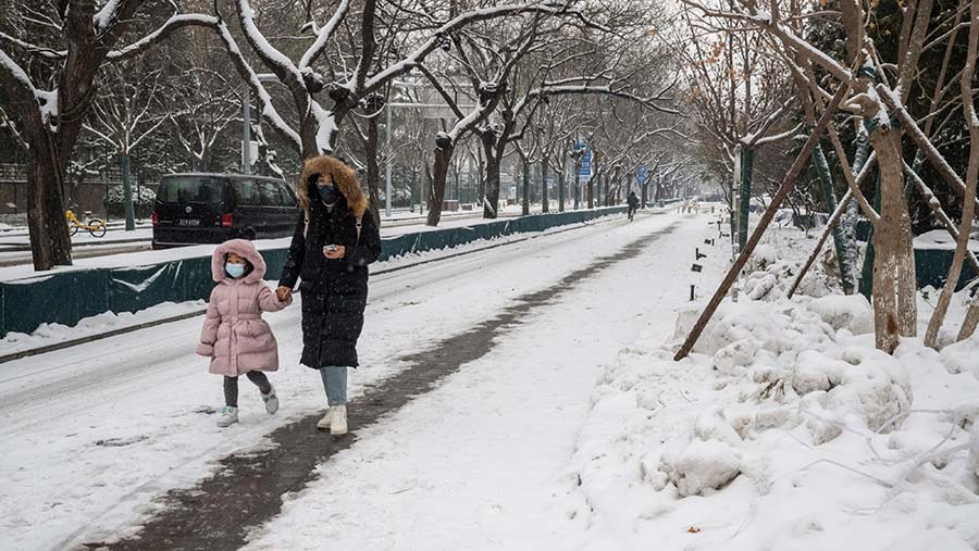 Pejalan kaki di sepanjang trotoar yang tertutup salju di Beijing, China, Kamis (14/12/2023). (Bloomberg)
