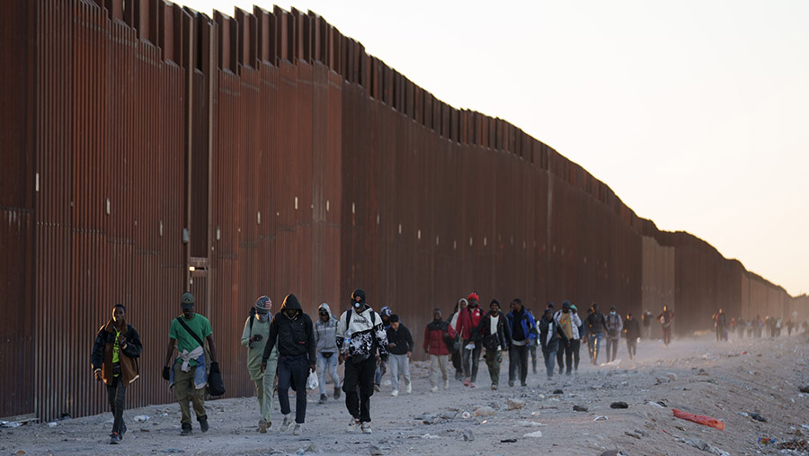 Para imigran berjalan di sepanjang pagar perbatasan AS-Meksiko di Lukeville, Arizona, AS, Selasa (12/12/2023). (Eric Thayer/Bloomberg)