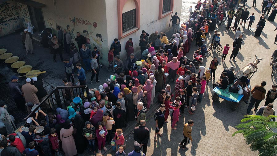 Warga Palestina antre untuk mengambil bantuan makanan gratis di Rafah, Gaza selatan, Senin (18/12/2023). (Ahmad Salem/Bloomberg)
