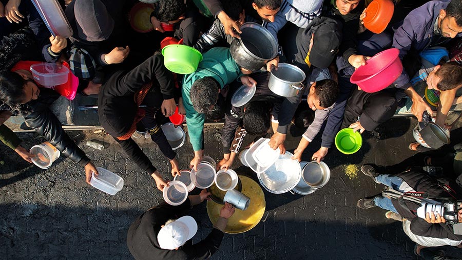 Warga Palestina membawa mangkok untuk mengambil makanan gratis di Rafah, Gaza selatan, Senin (18/12/2023). (Ahmad Salem/Bloomberg)