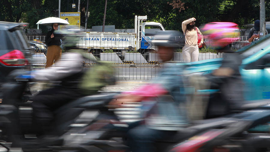 Warga berjalan saat cuaca panas di Jakarta, Selasa (19/12/2023). (Bloomberg Technoz/Andrean Kristianto)