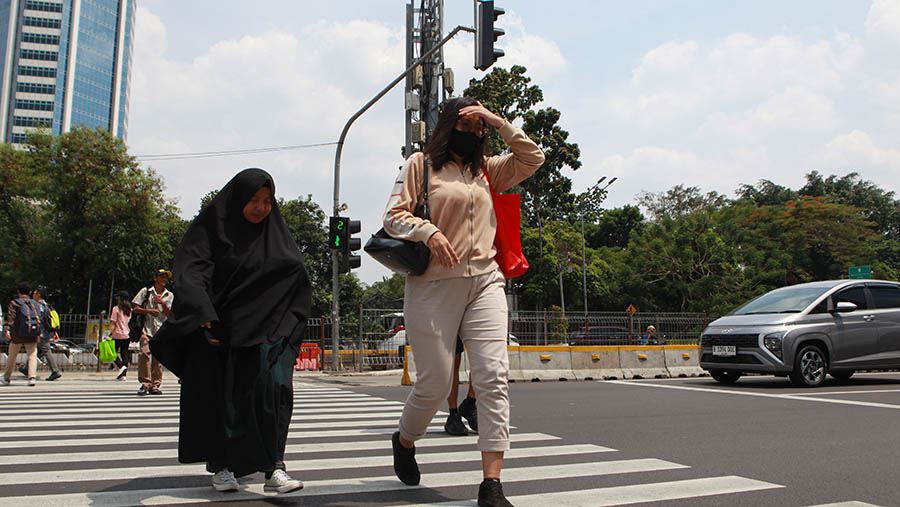 Warga berjalan saat cuaca panas di Jakarta, Selasa (19/12/2023). (Bloomberg Technoz/Andrean Kristianto)
