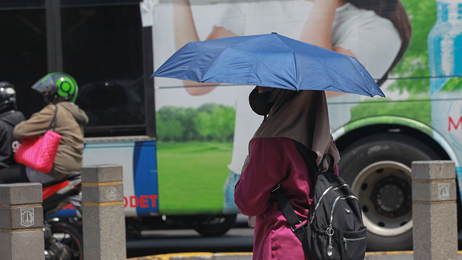 Warga berjalan saat cuaca panas di Jakarta, Selasa (19/12/2023). (Bloomberg Technoz/Andrean Kristianto)