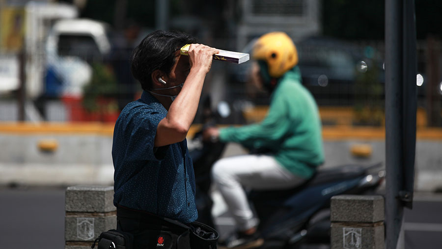Warga berjalan saat cuaca panas di Jakarta, Selasa (19/12/2023). (Bloomberg Technoz/Andrean Kristianto)