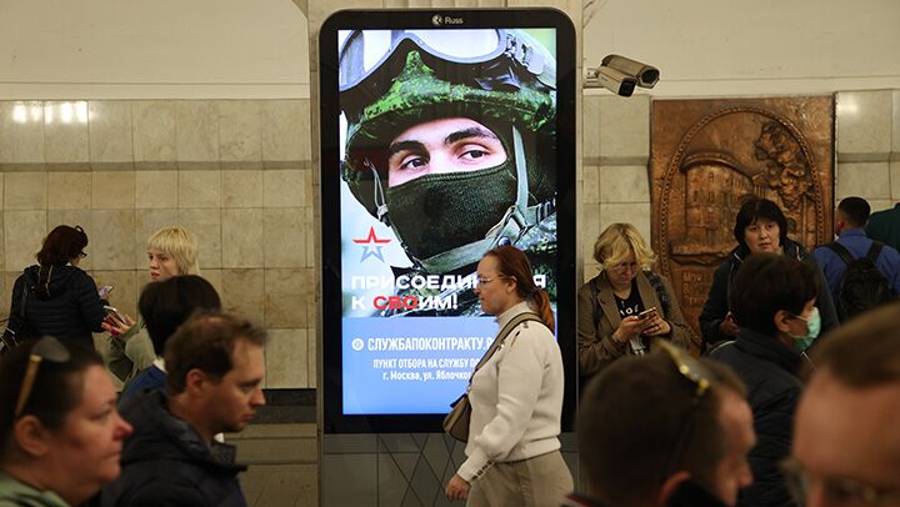 Passengers walk past a billboard advertising contract service in the army, at a subway station in Moscow. (Dok: Bloomberg)