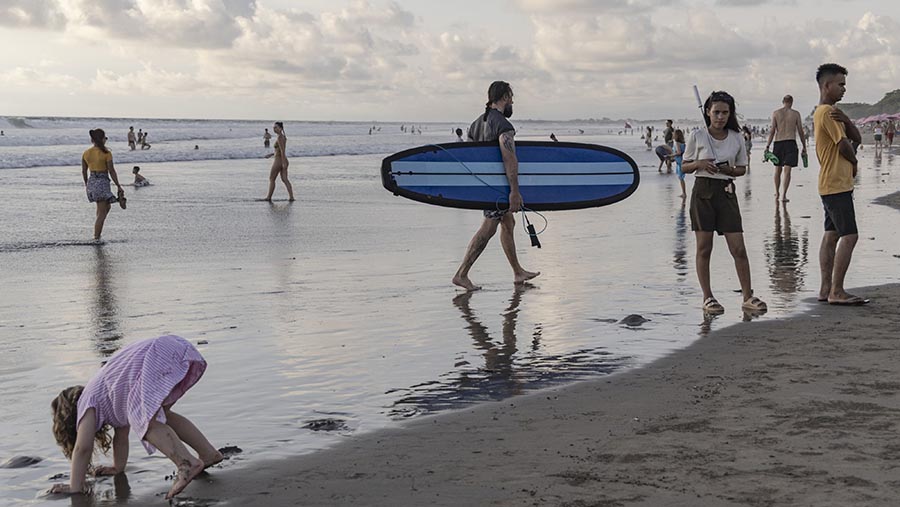 Wisatawan mengunjungi pantai Double Six di Seminyak, Bali, Selasa (26/12/2023). (Nyimas Laula/Bloomberg)