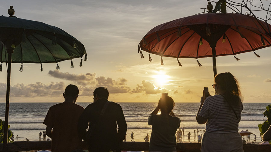 Pengunjung menyaksikan matahari terbenam di pantai Double Six di Seminyak, Bali, Selasa (26/12/2023). (Nyimas Laula/Bloomberg)
