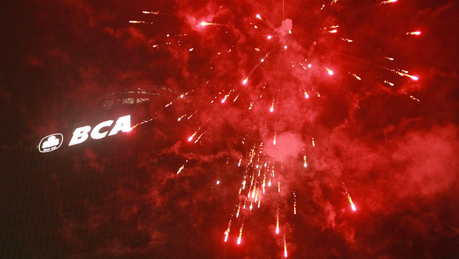 Kembang api menyala di samping logo BCA saat malam pergantian tahun di Bundaran HI, Senin (1/1/2024). (Bloomberg Technoz/Andrean Kristianto)